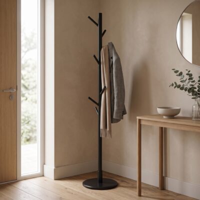 Zwarte staande kapstok met meerdere haken, jas en sjaal in een lichte hal naast een houten sidetable