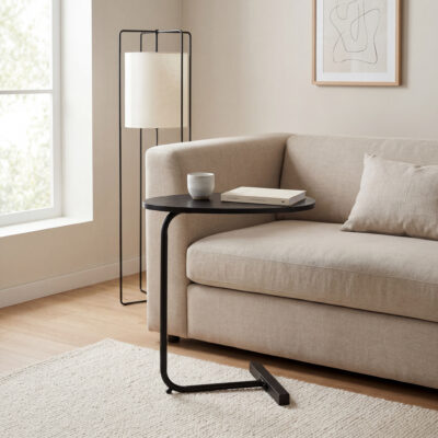 Lichte woonkamer met zwarte bijzettafel naast een beige bank, vloerlamp en minimalistische wanddecoratie