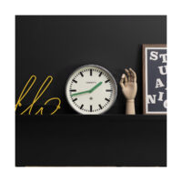Modern industrial Luggage wall clock by Newgate Clocks with a galvanised finish, chunky marker dial and green hands on a shelf - LUGG667GALVG