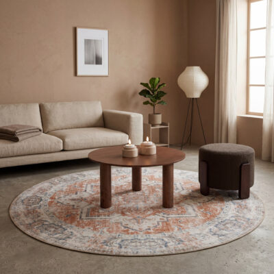Warme woonkamer met ronde houten salontafel, beige bank, donkerbruine poef en rond vintage vloerkleed