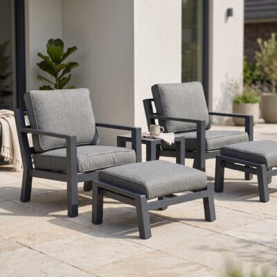 Grijze loungeset met twee fauteuils, voetenbankjes en bijzettafel op een zonnig terras